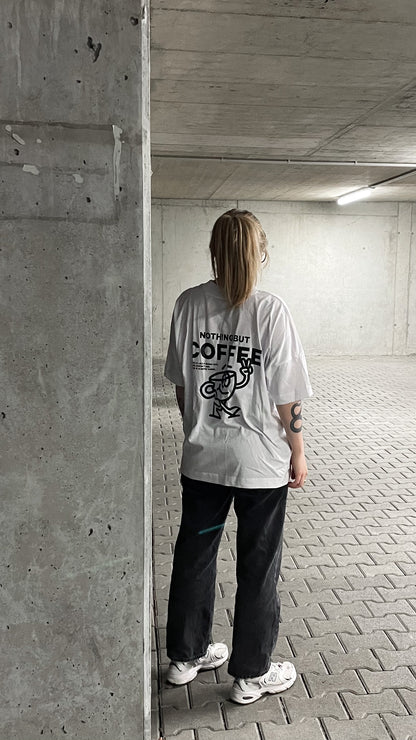 weißes coffee club shirt mit schwarzem Aufdruck "nothing but coffee", Rückenansicht, getragen von einer weiblichen Person in einem leeren Parkhaus