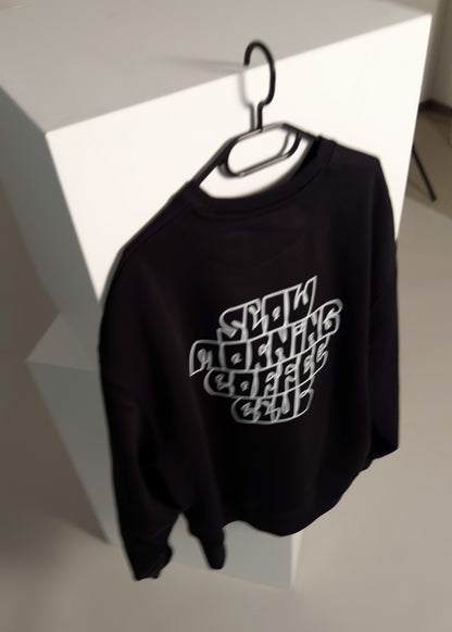 slow morning coffee club sweater schwarz, auf einem Kleiderbügel hängend